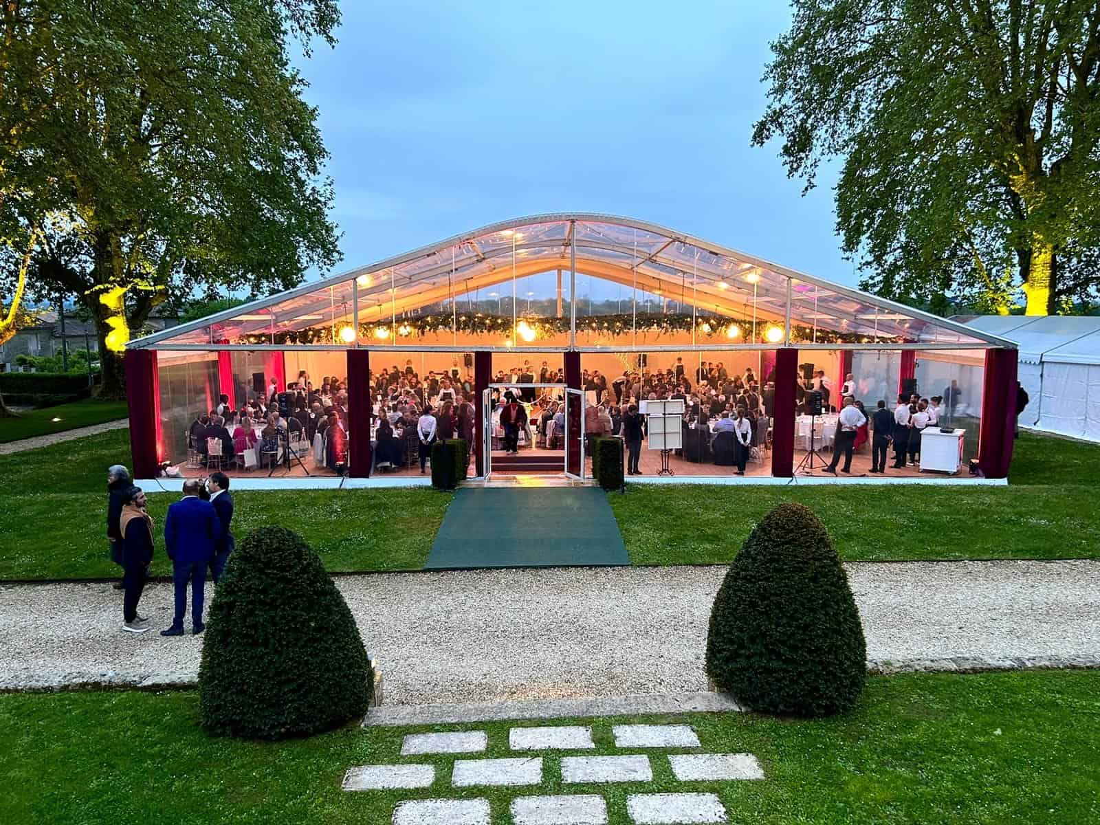 Large transparent event tent set up outdoors at Bellefont Belcier Castle with guests inside.