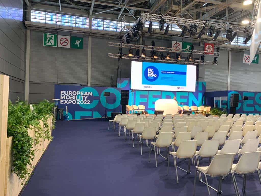 Conference stage at European Mobile Innovation Expo 2022 with seating and presentation screens.