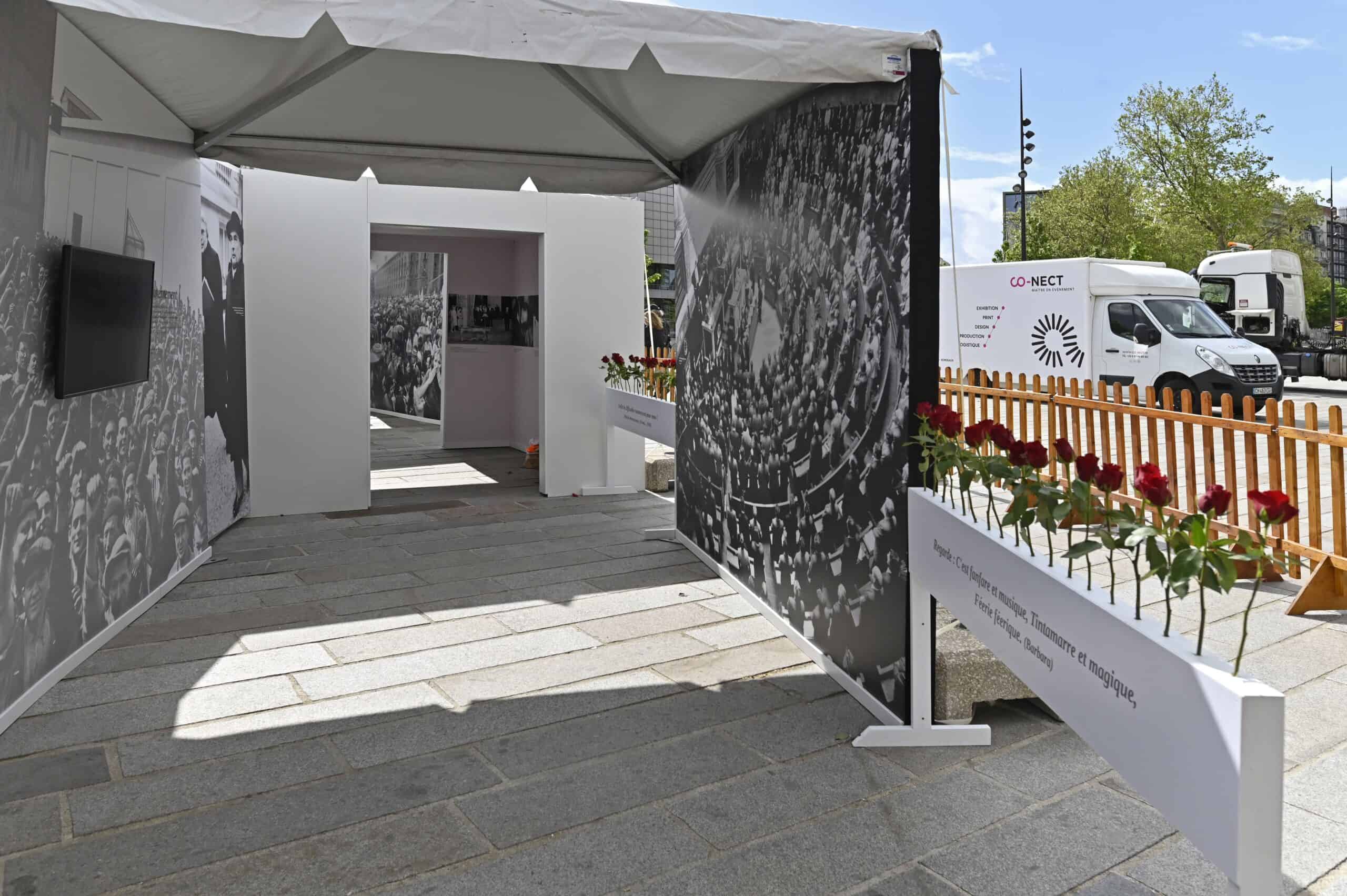 Exposition Co-Nect lors de l'anniversaire de Mitterrand, espace extérieur avec affiches et roses.