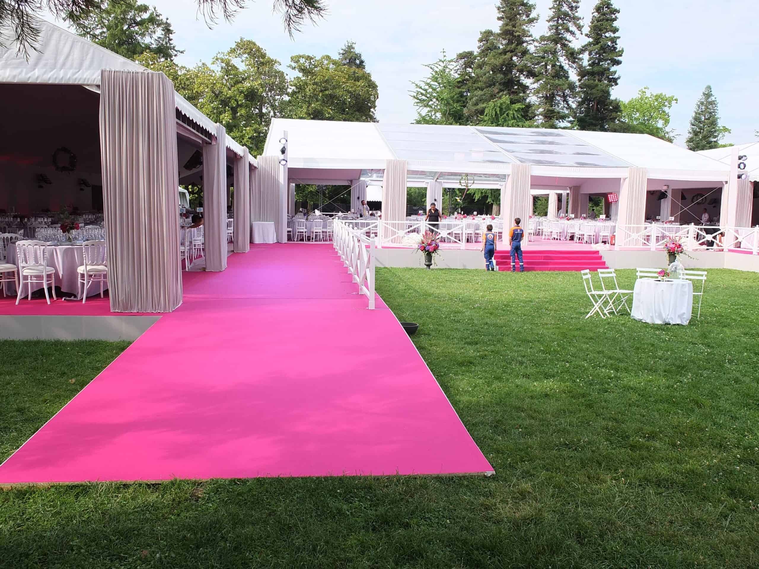 Elegant outdoor event setup with pink carpet and white tents for a flower festival.