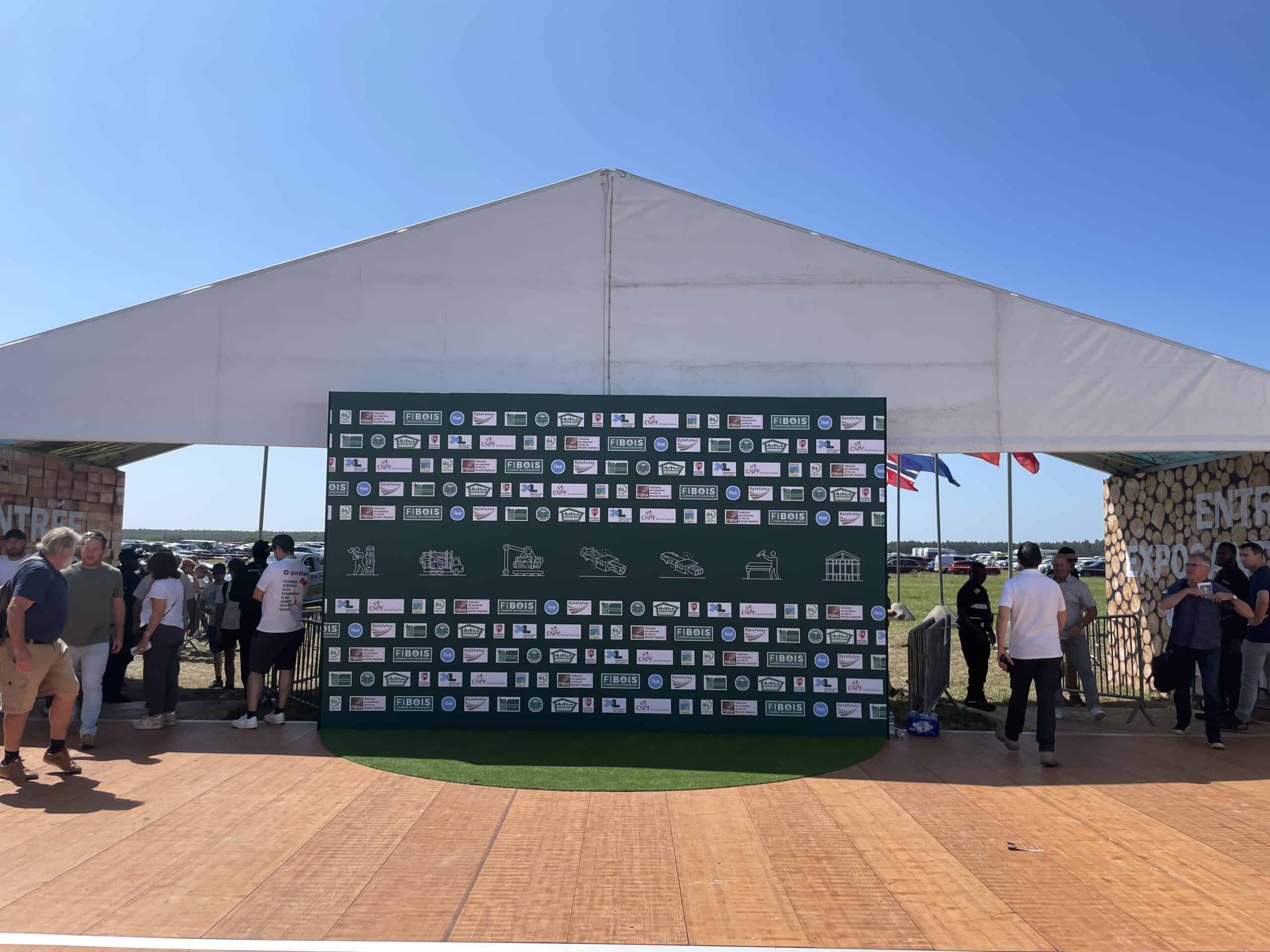 Large event tent at FOREXPO with sponsor banners and attendees outside.