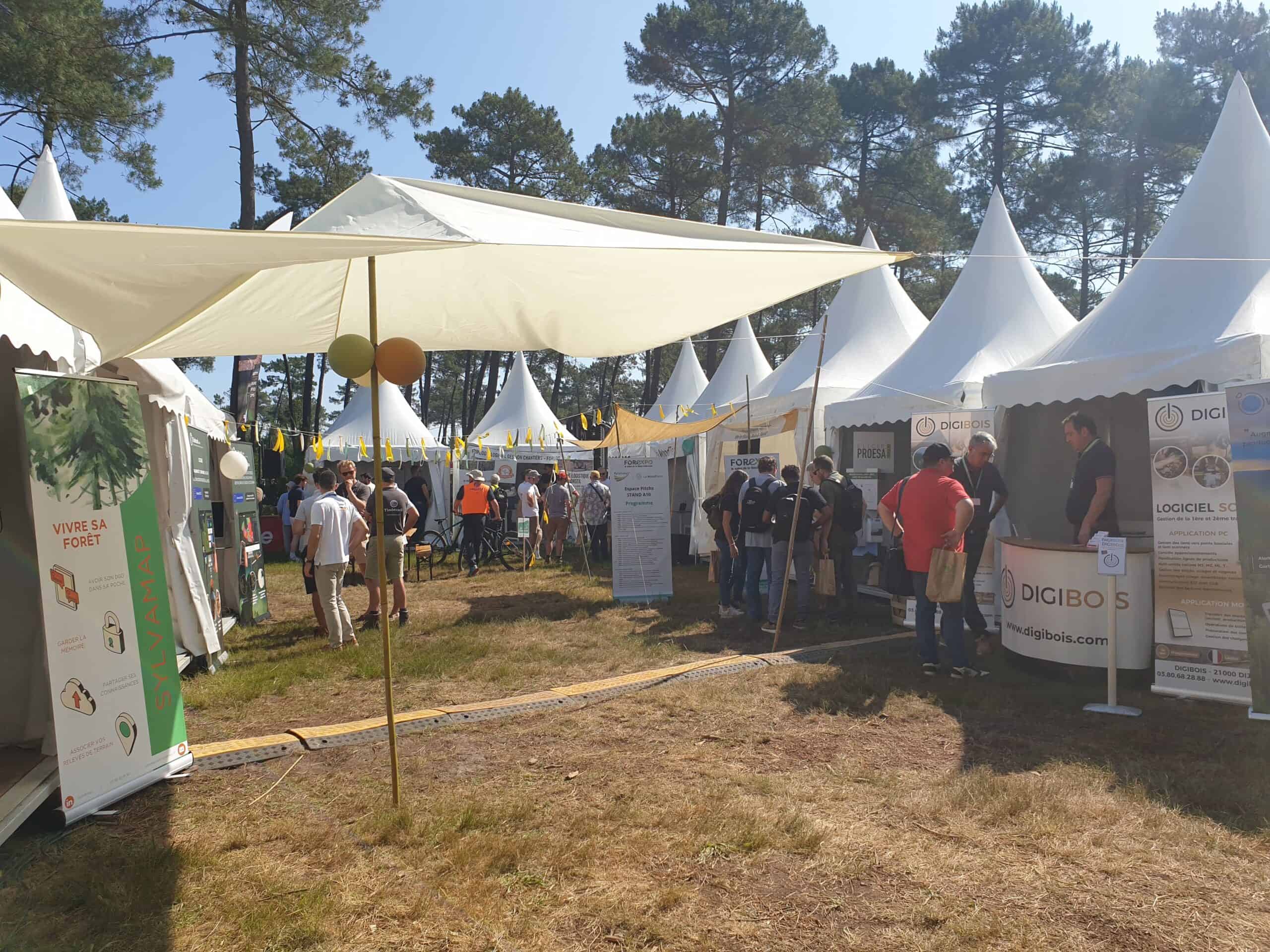 Outdoor tech exhibition with white tents and visitors at FOREXPO event.