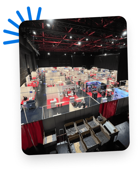 Exhibition hall with multiple booths and attendees at Co-Nect event.