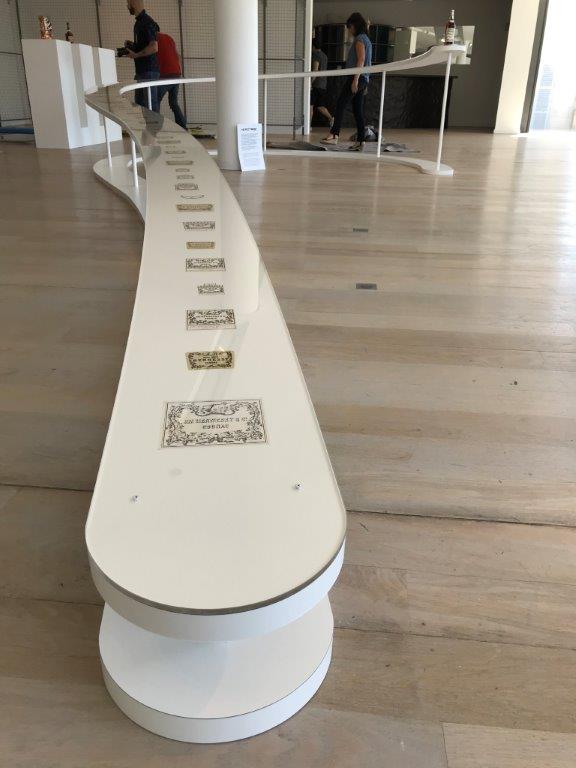 Curved white display with various banknotes in an art exhibit.