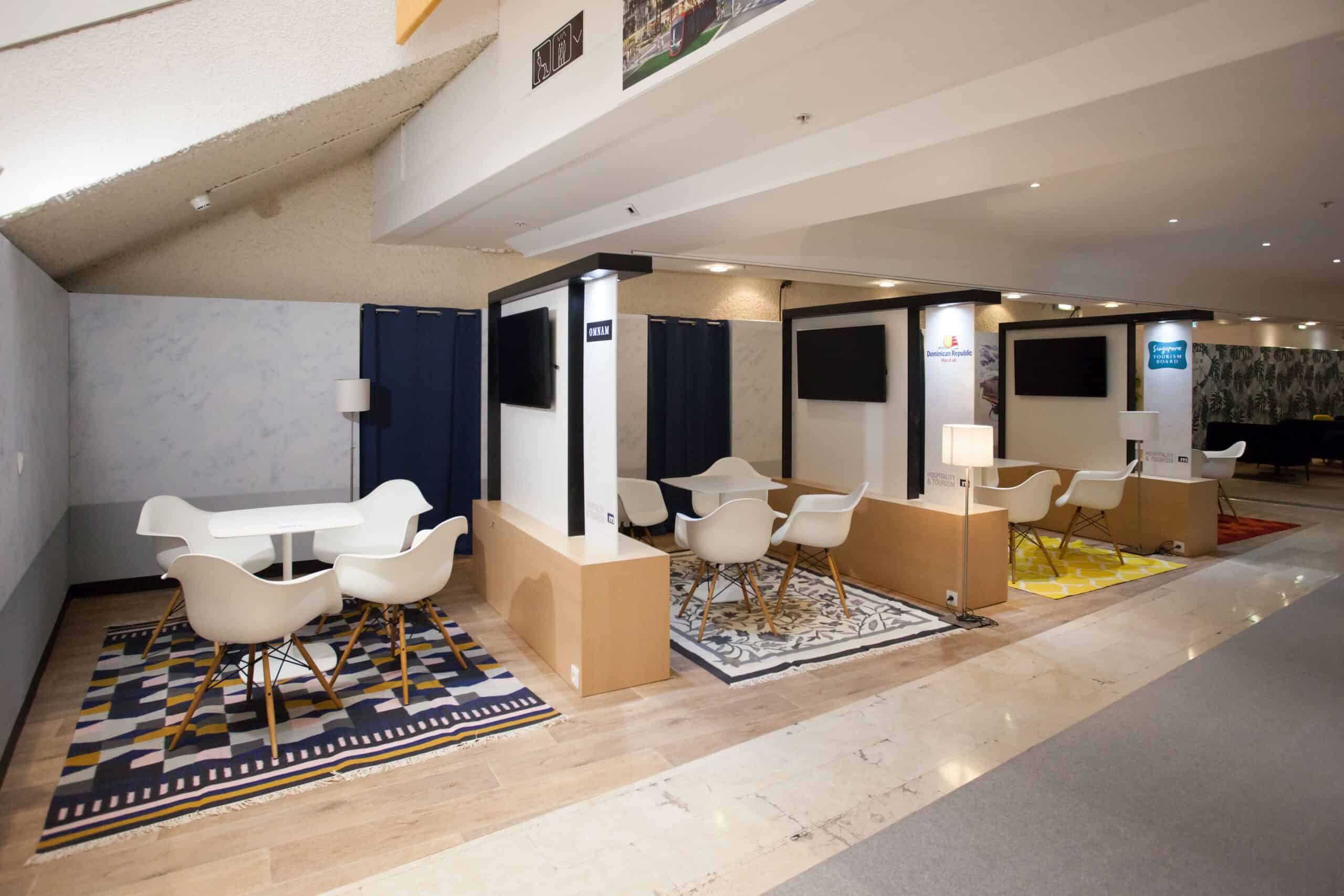 Espace d'accueil pour événementiel avec stands et mobilier moderne.
