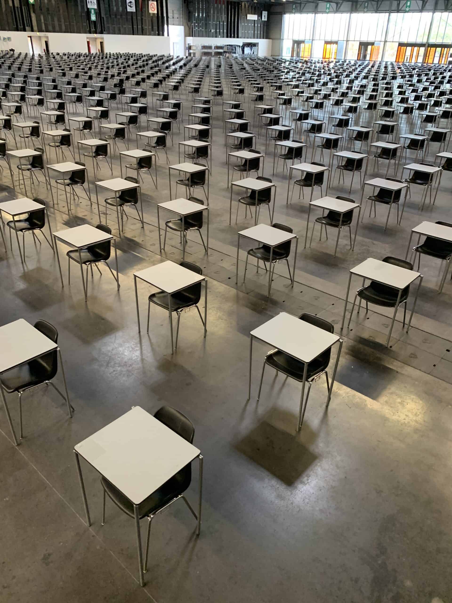 Empty classroom with rows of desks and chairs arranged for exams or training.