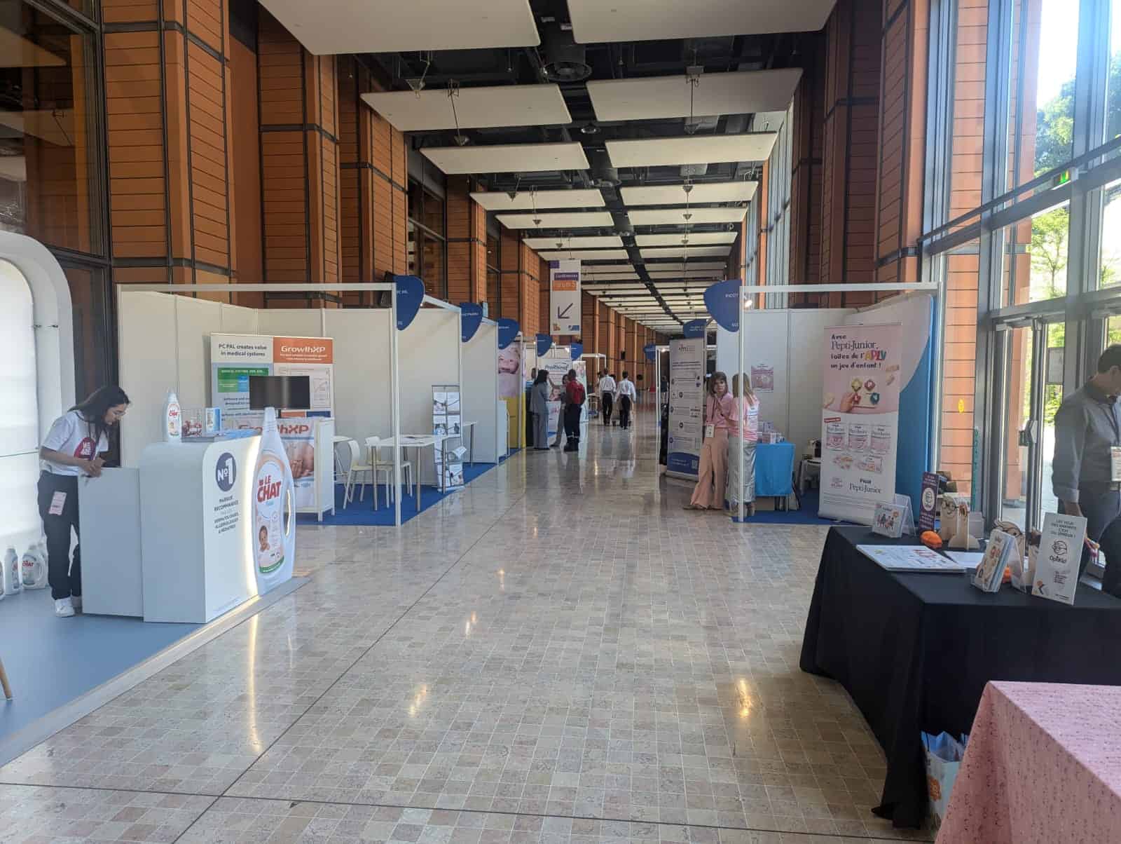 Indoor view of a pediatric conference with exhibitor booths and attendees.