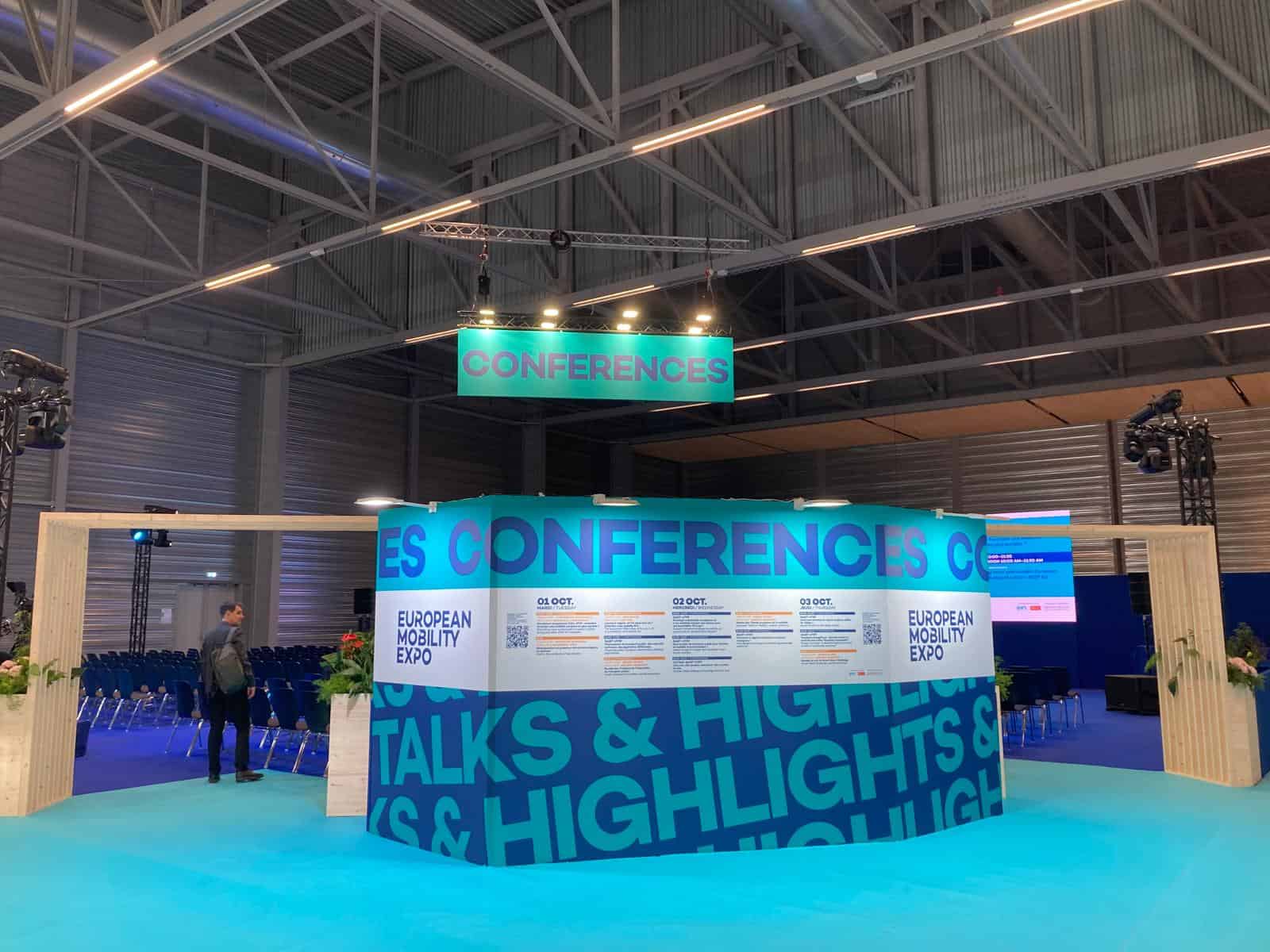 Conference booth at European Mobility Expo with digital displays and signage.