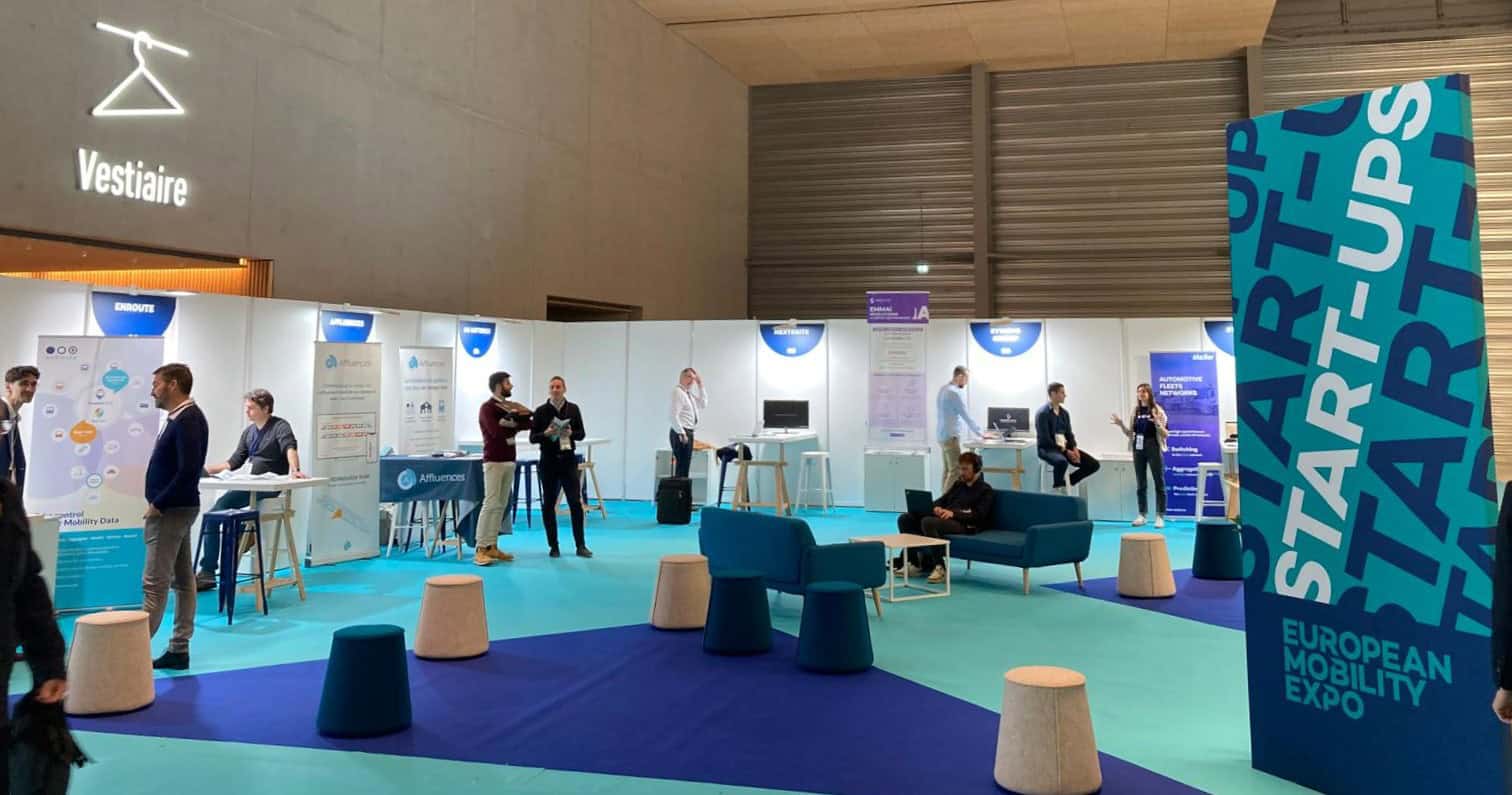 European startup and innovation exhibition booth with attendees and displays.