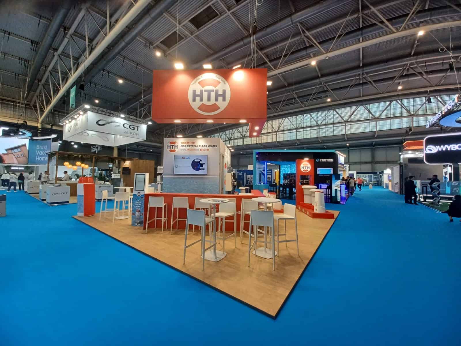 HTH exhibition booth at a trade show with seating and branding displays.