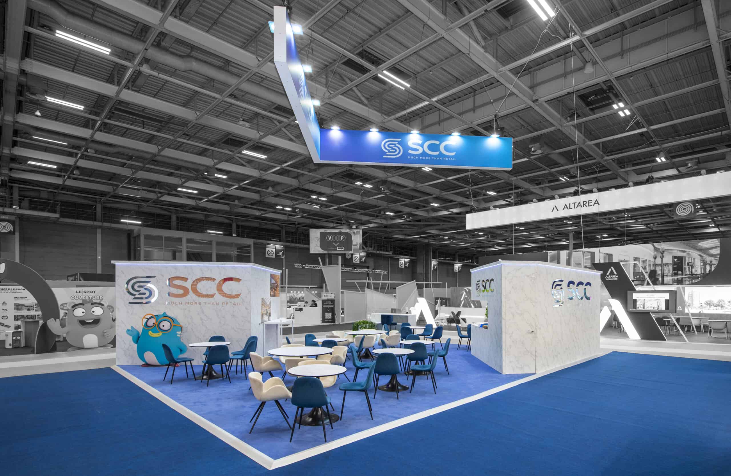 SCC trade show booth with seating area and branding displays.