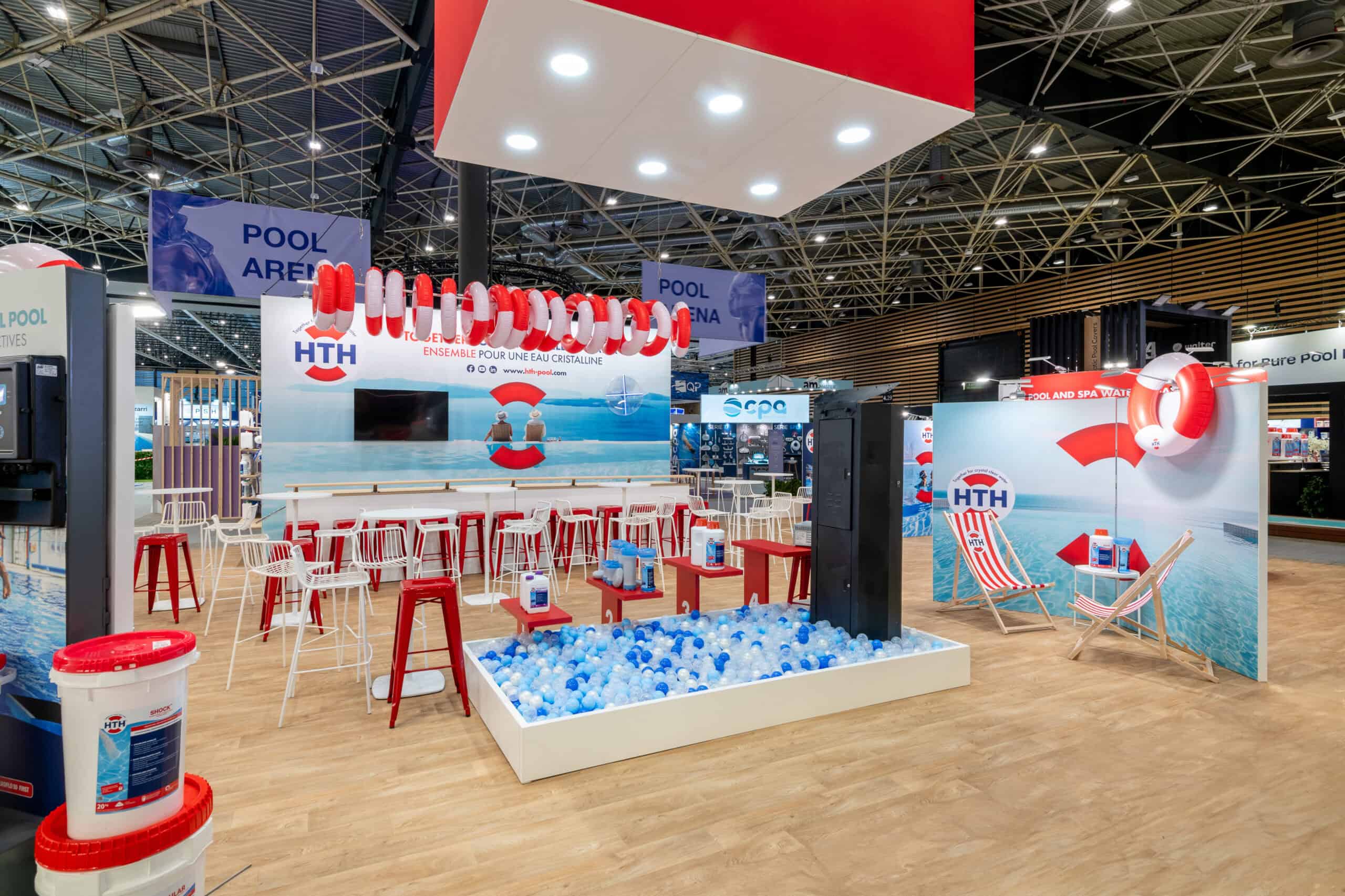 Co-Nect booth at HTH pool exhibition with pool toys and lounge area.