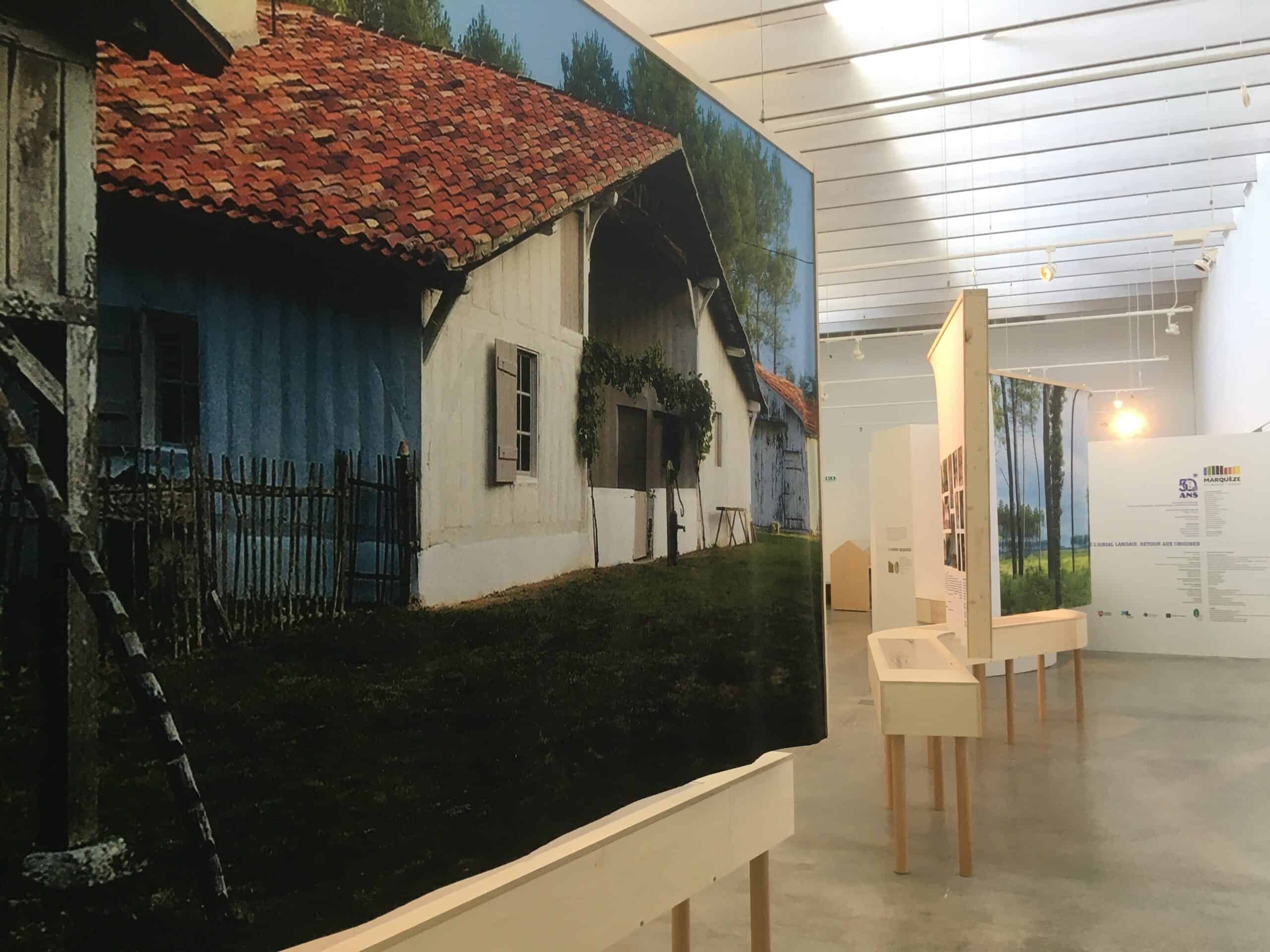Stand d'exposition avec maquette d'une maison traditionnelle en intérieur.